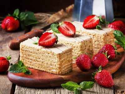 Traditional russian honey cake decorated with strawberries and g Traditional russian honey cake decorated with strawberries and green mint, old wooden background, selective focus